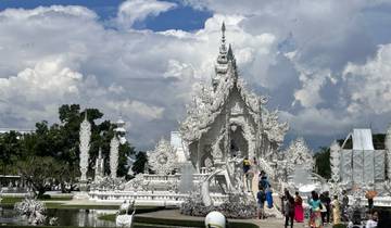 White ornate temple with people visiting.