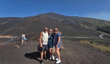 Three people posing in front of a large mountainous landscape.