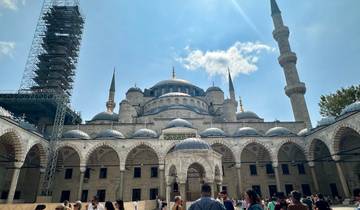 Historic mosque with domes and a scaffolded minaret.