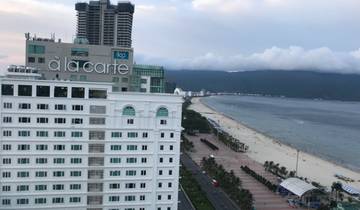 A view of a beachside hotel with the sea and mountains.