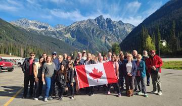 Group of people holding a Canadian flag with mountains in the background.