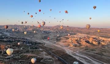 A sky full of colorful hot air balloons over a landscape.
