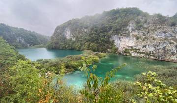 A view of a lake surrounded by lush greenery and cliffs.