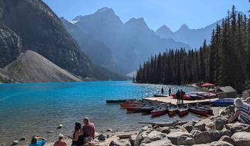 Canoes docked at a lake with mountains in the background.