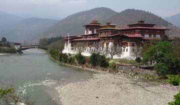 Dzong beside a river with mountains in the background.