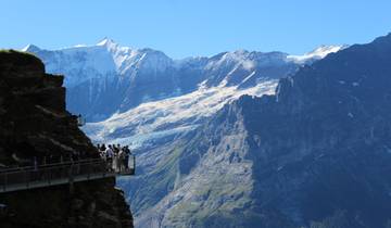 Tourists on a viewing platform with a mountain backdrop.