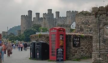 Castle with people and a red phone booth in front.