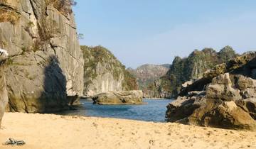 Sandy beach with large rock formations in front of the sea.