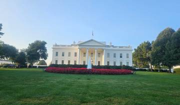 The White House with landscaped gardens in front and a clear blue sky.