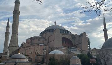 Historic mosque with domes under a partly cloudy sky.
