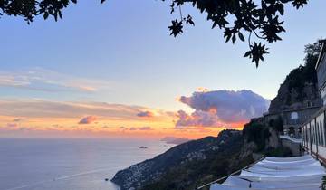 Sunset over a coastal landscape with calm sea.