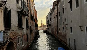 Narrow canal with a view of a distant bell tower in Venice.