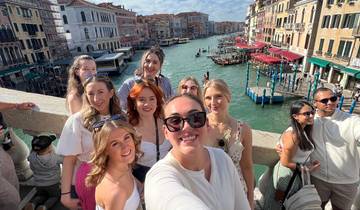 Group of friends posing on a bridge with a canal and historic buildings in the background.