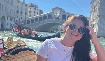Woman on a gondola with the Rialto Bridge in the background.