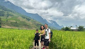 Family walking through rice paddies with mountains in the background.