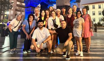 Group of people posing at night in front of blue-lit structure.