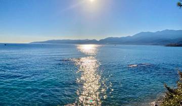 Sparkling sunlight reflecting on a calm sea with mountainous coastline