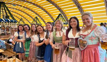 Group of women in traditional Bavarian clothing holding beer mugs inside a festival tent