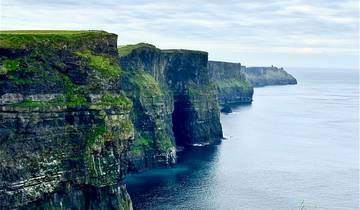 Cliffs overlooking the sea with a green landscape.