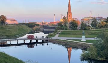 Scenic park with canals and church spire at dusk.