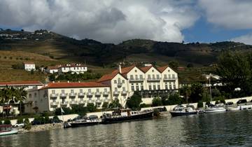 Scenic view of a river with buildings and terraced hills in the background.