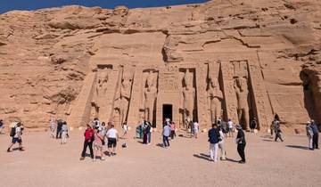 People visiting an ancient temple carved into a rock face.
