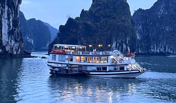 A boat sailing through scenic karst formations during twilight.