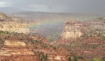 Scenic canyon landscape with colorful rock formations and a faint rainbow.