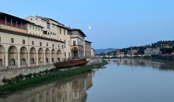 River view with historical buildings and a moon in Florence.