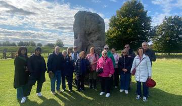A group of people posing in front of a large stone monument.