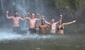 Group of people posing under a waterfall.