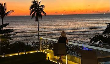 Person sitting and watching the sunset over the ocean.