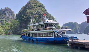 Tourist boat docked in a bay surrounded by limestone mountains.