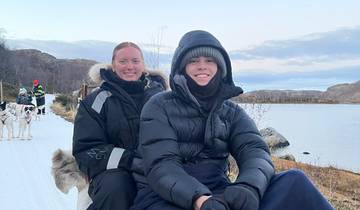 Two people dressed warmly dogsledding.
