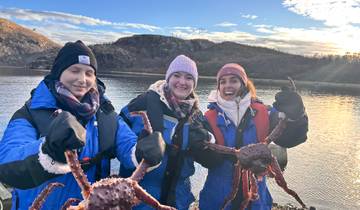 Three people holding crabs near water.