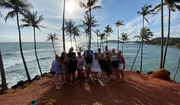 Group of people posing in front of palm trees by the ocean