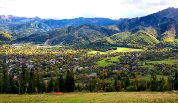 Panoramic view of a town surrounded by mountains in autumn.