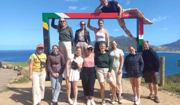 Group of people posing under a large frame with a scenic background.