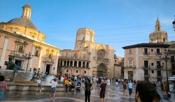 A bustling plaza with historic buildings and a fountain.