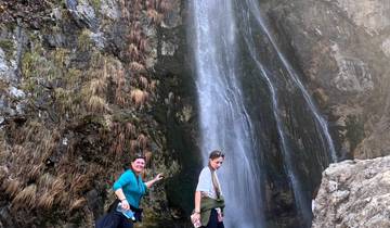 Two people standing in front of a waterfall.