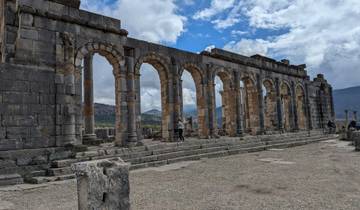 Roman ruins with arches and tourists.
