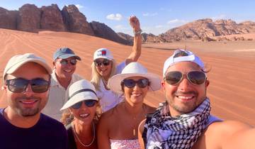 Group of six people smiling and posing in desert scenery.
