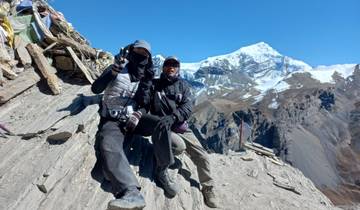 Two trekkers posing with a snowy mountain in the background.