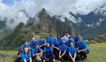 Group of tourists posing with Machu Picchu ruins in the background.