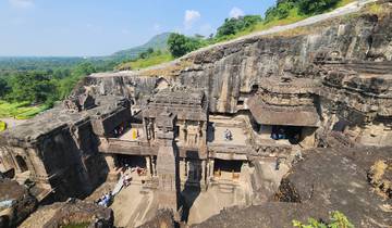 People exploring large ancient stone structures carved into the hillside.