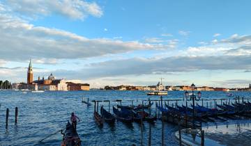 View of gondolas with a backdrop of Venice skyline and water.