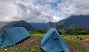 Tents pitched on a grassy area with mountain views.