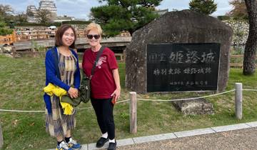 Two women posing next to a historic sign and garden.