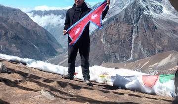 Person holding a flag in a snowy mountainous landscape.