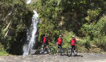 Cyclists wearing helmets posing in front of a waterfall.